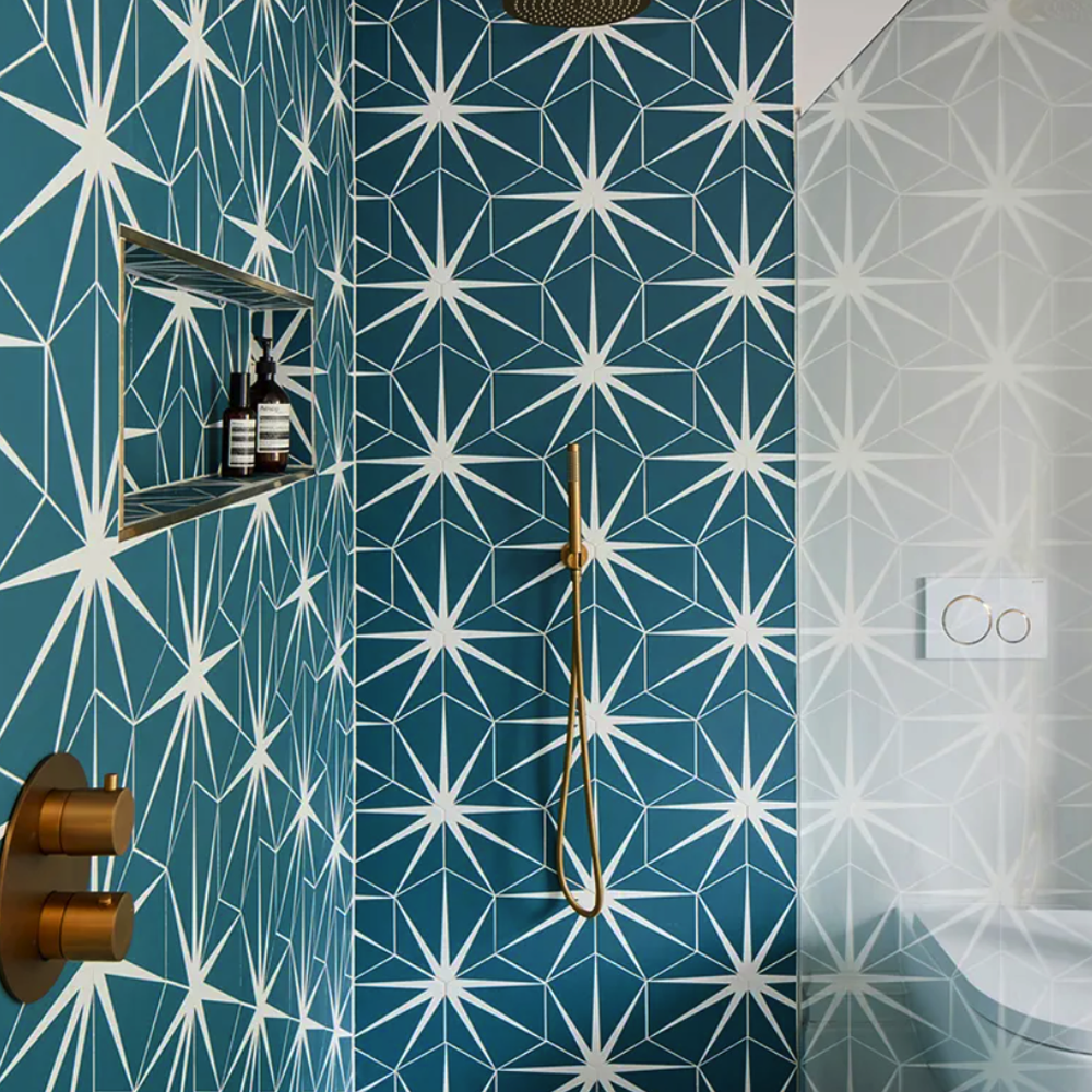 Bathroom with blue and white geometric tile pattern and gold fixtures.