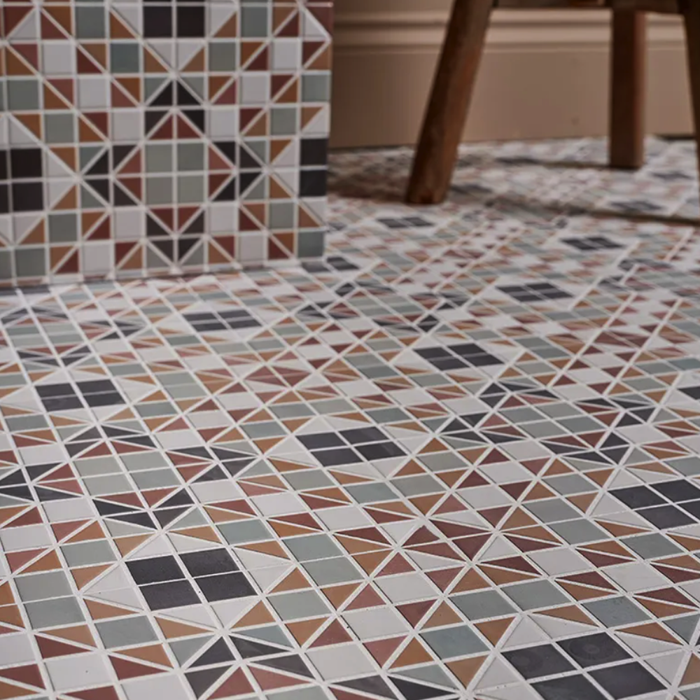 Geometric patterned tiles on a floor with a chair leg visible