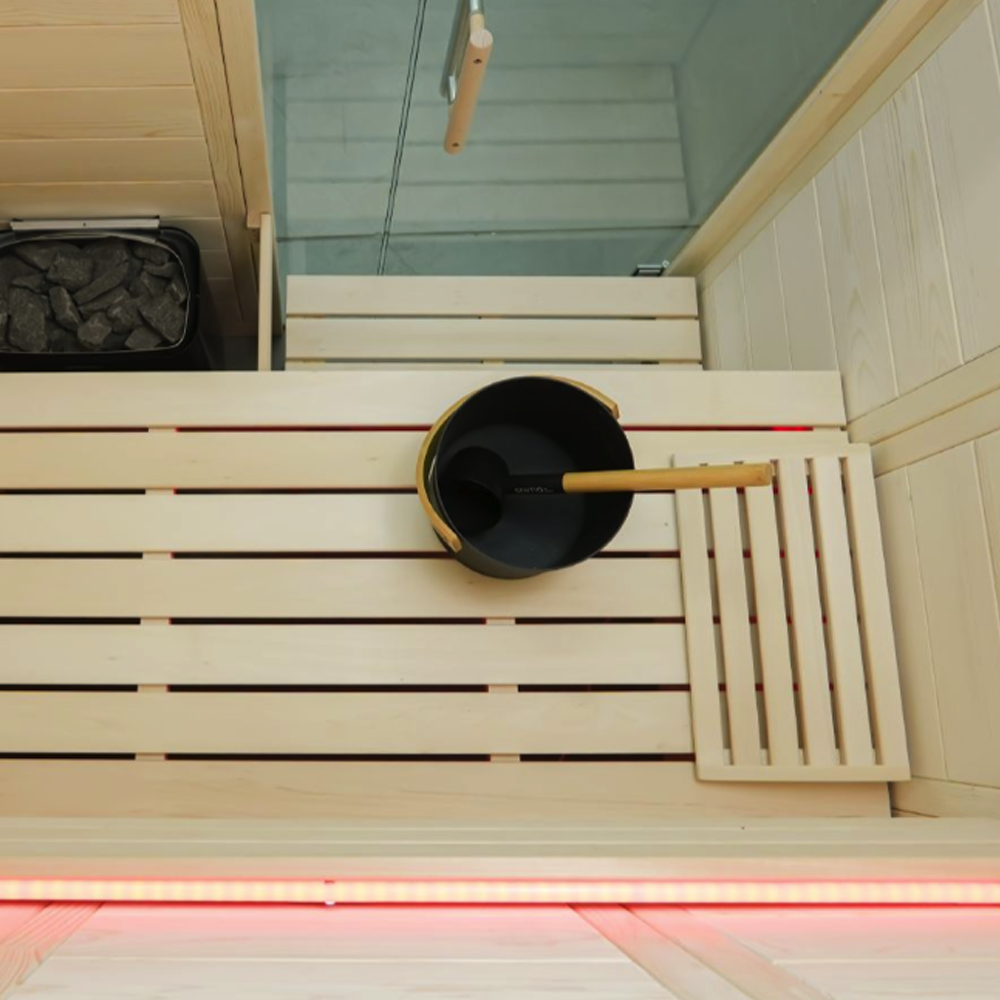 Black pot with wooden handle on a wooden bench inside a sauna
