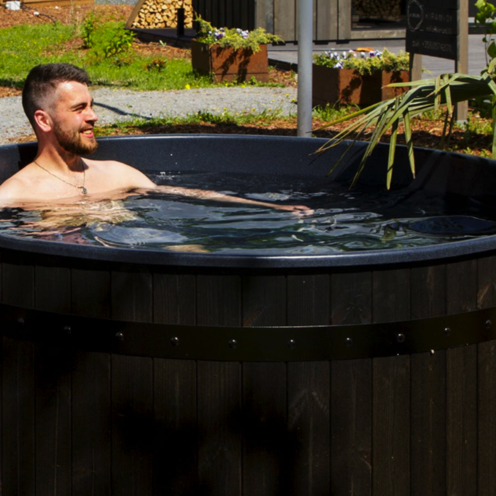 Man relaxing in a hot tub outdoors with greenery around