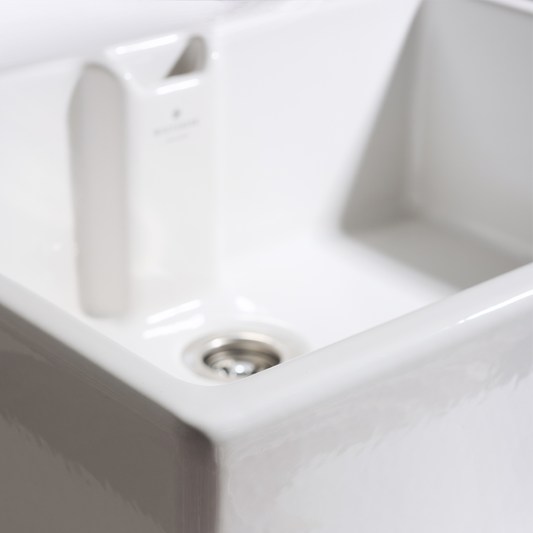 Close-up of a white ceramic sink with a metallic drain.