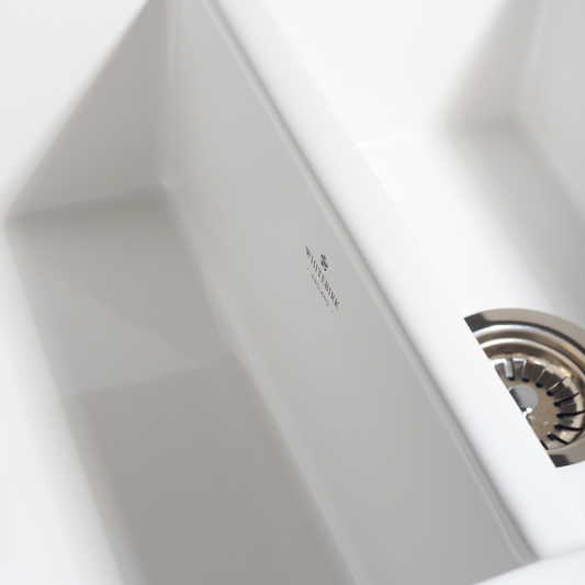 Close-up of a white hand dryer with a brand logo on a light gray background