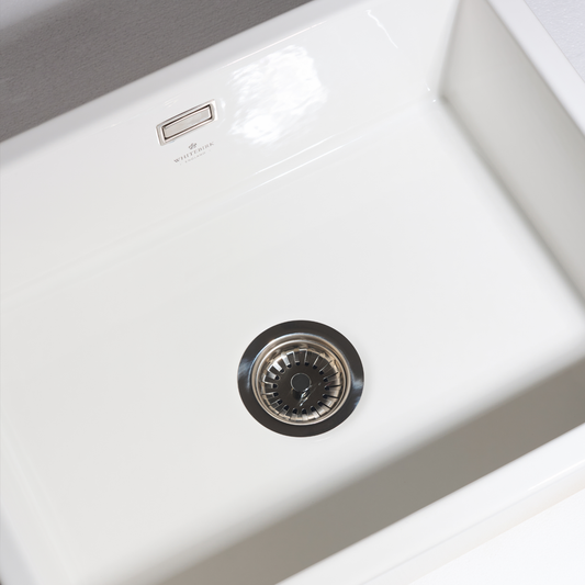 Close-up of a white kitchen sink with a drain cover