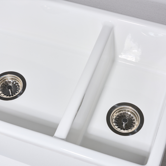 Close-up of a white kitchen sink with two basins and drain holes.