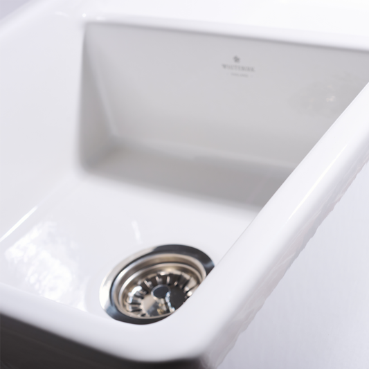 Close-up of a white kitchen sink with a drain