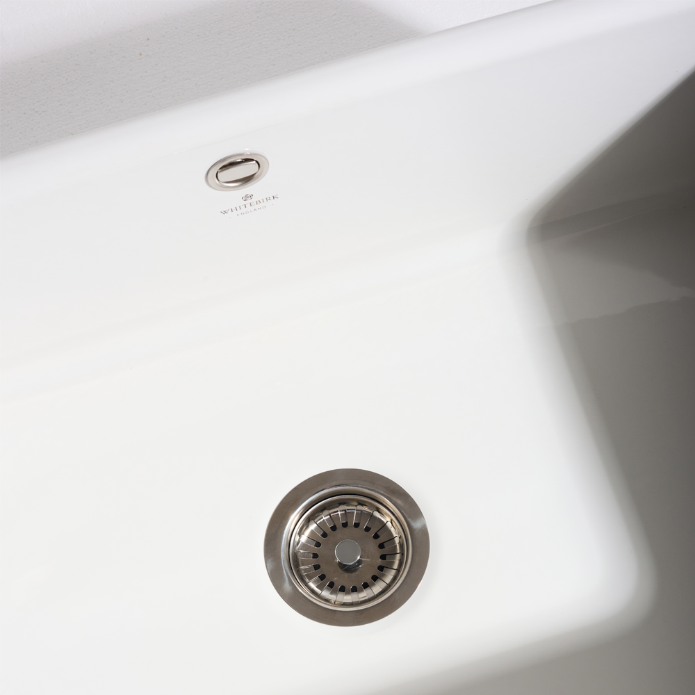 Close-up of a white kitchen sink with a visible brand logo.