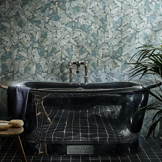 Black freestanding bathtub in a bathroom with leaf-patterned wall tiles.