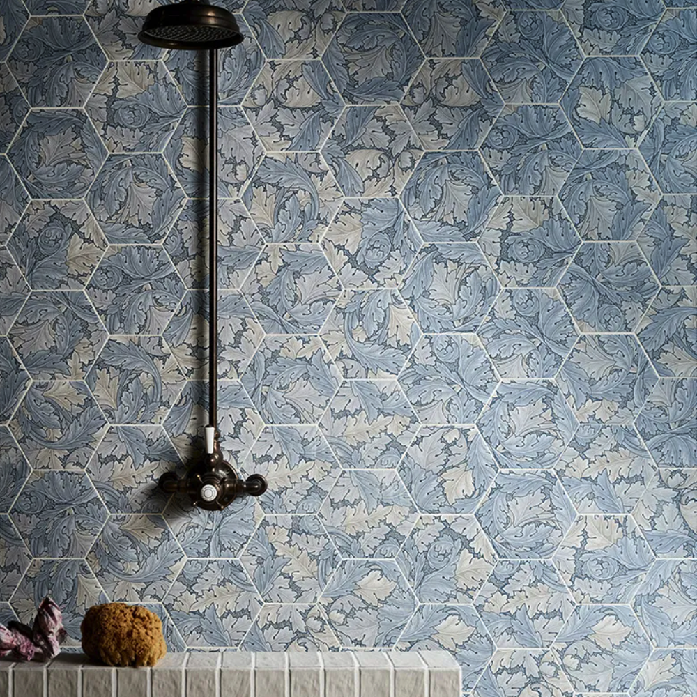 Hexagonal blue tiles with a shower head and soap dish on a tiled wall.