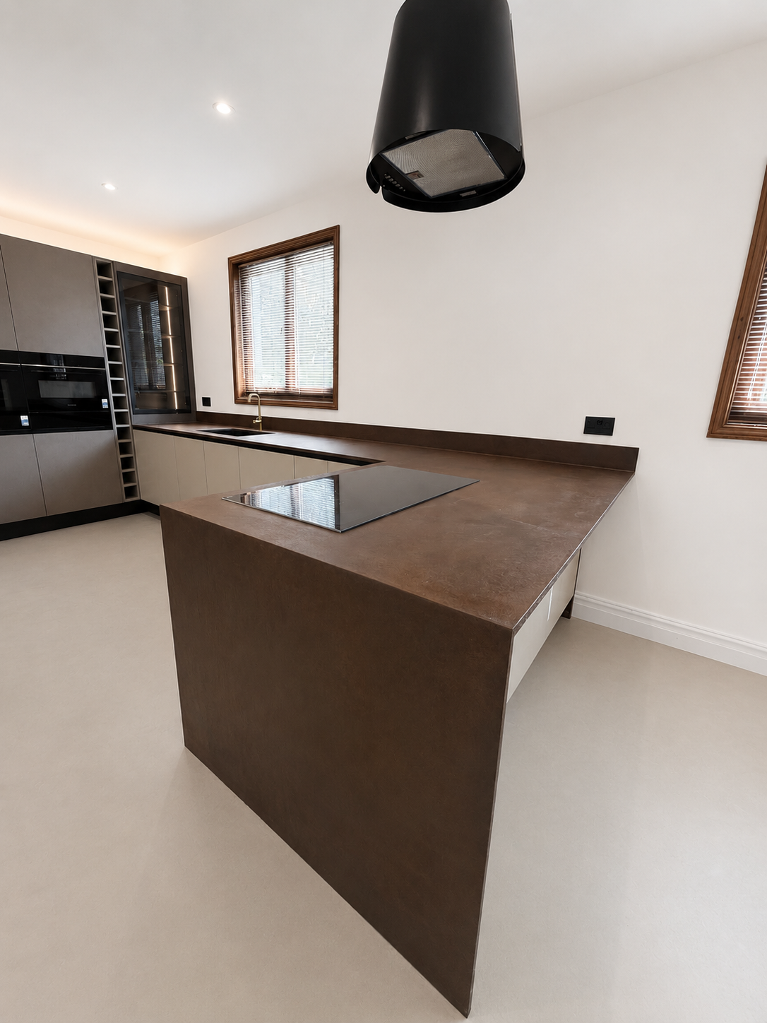 Oxidised Liquid Metal Iron worktop with waterfall end panel on a Microstone poured floor