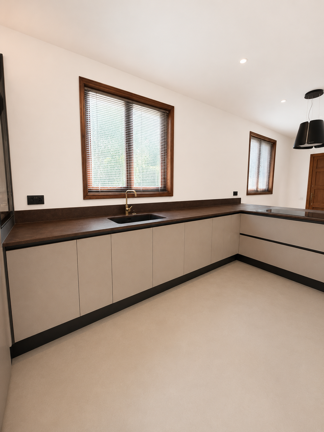 Greige handleless base units with oxidised iron worktop and brushed brass tap