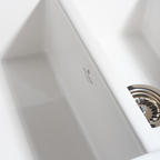 Close-up of a white hand dryer with a brand logo on a light gray background