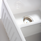 Close-up of a white kitchen sink with a silver drain.