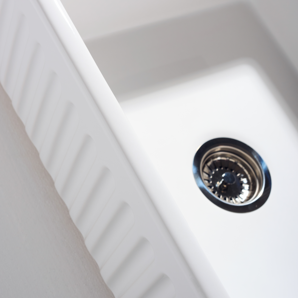 Close-up of a white kitchen sink with a drain
