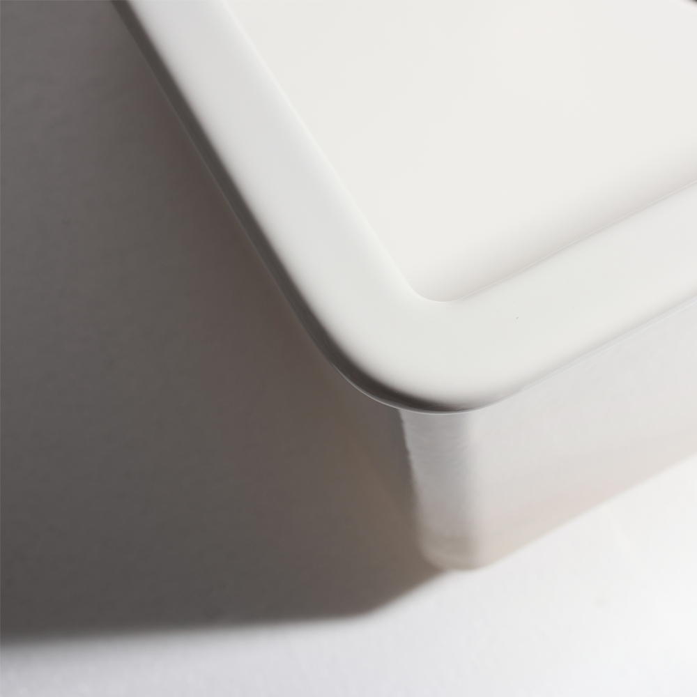 Close-up of a white ceramic sink corner on a gray background