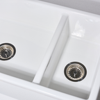 Close-up of a white kitchen sink with two basins and drain holes.