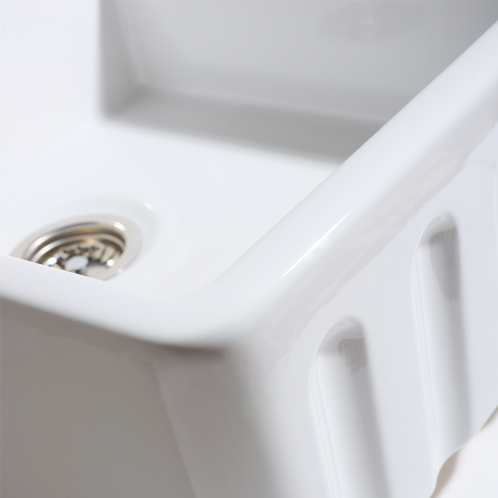 Close-up of a white ceramic kitchen sink with a drain.