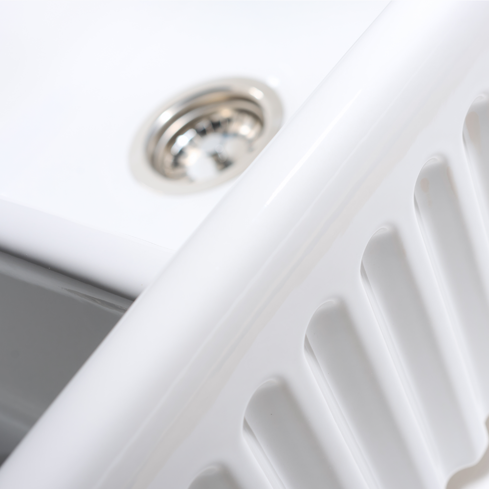 Close-up of a white kitchen sink with a silver drain.