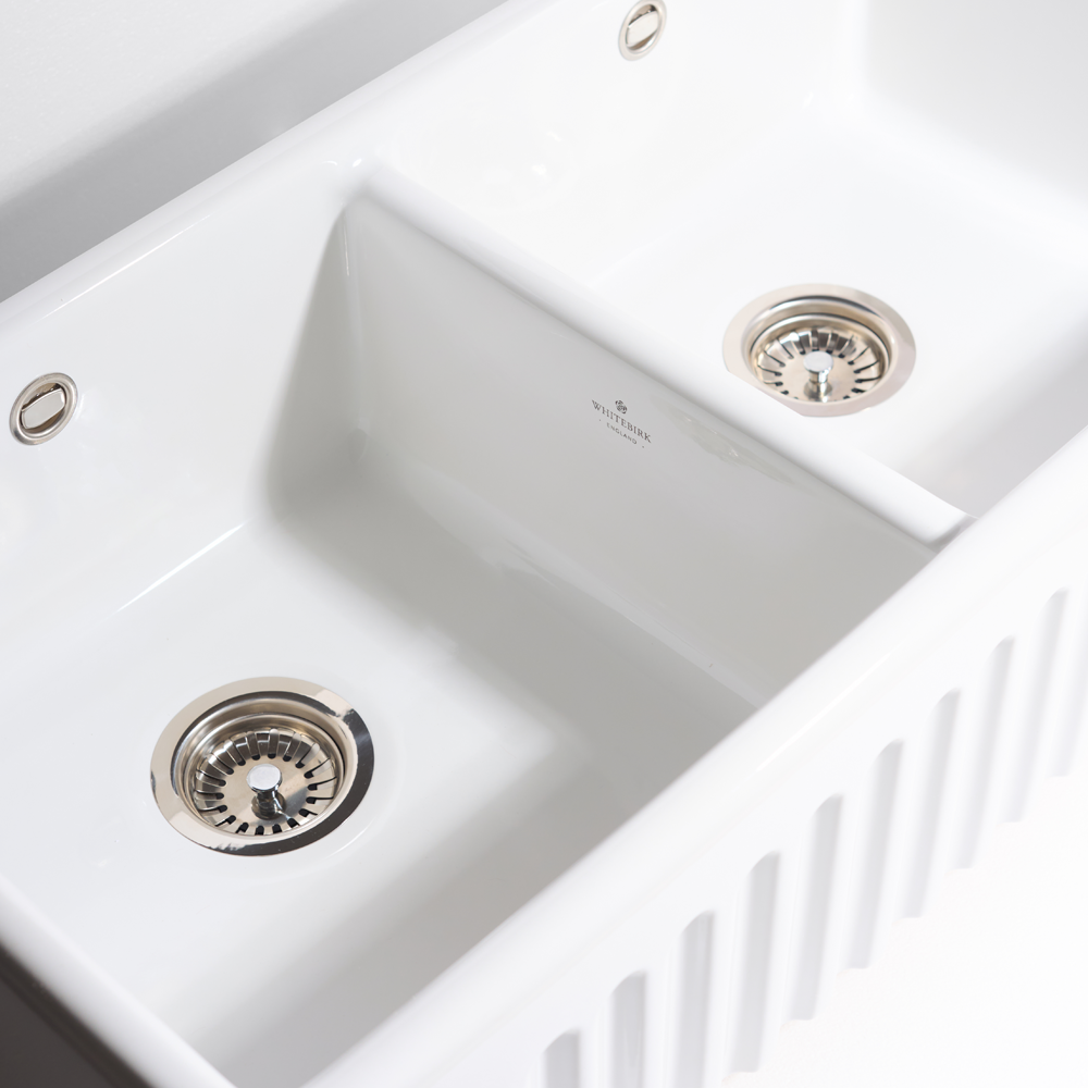 White kitchen sink with two drainboards and visible brand name.